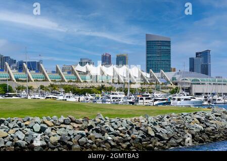 Blick auf den futuristischen, modernen Komplex des San Diego Convention Center am Wasser mit Booten, die an der Marina und der felsigen Küste von San Diego, CA, angedockt sind Stockfoto