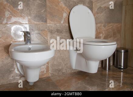 Eine Toilette und ein Bidet zum Waschen der Genitalien sind im Badezimmer kombiniert. Toilettenausstattung, braune Keramikfliesen Stockfoto