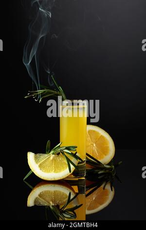 Traditioneller hausgemachter Zitronenlikör Limoncello und frische Zitrusfrüchte auf dem schwarzen reflektierenden Hintergrund. Italienische traditionelle Likör Limoncello mit Zitrone s Stockfoto