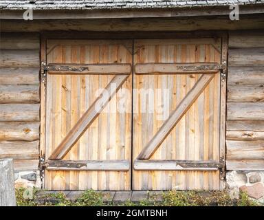 Holztor in einem Blockschuppen im Dorf und schmiedeeiserne Scharniere, alte Architektur Stockfoto