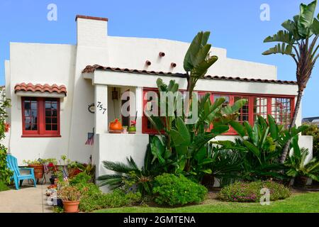 Ein altes, cremeweißes Haus im kalifornischen Bungalowstil mit roten Zierleisten und wunderschöner Küstenvegetation auf Coronado Island, San Diego, CA Stockfoto