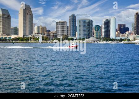 Ein Kabinencruiser-Boot fährt im Hafen von San Diego mit einer atemberaubenden und modernen Stadtlandschaft von San Diego, CA, die vom Hafen von San Diego aus betrachtet wird Stockfoto