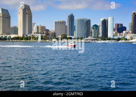 Ein Kabinencruiser-Boot fährt im Hafen von San Diego mit einer atemberaubenden und modernen Stadtlandschaft von San Diego, CA, die vom Hafen von San Diego aus betrachtet wird Stockfoto