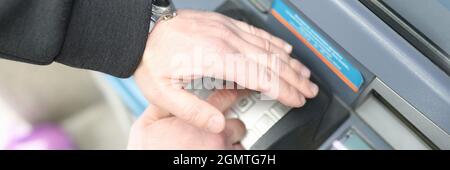 Man gibt Code auf der ATM-Tastatur ein und schließt ihn mit Seine Hand Stockfoto