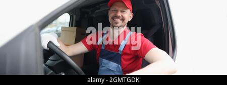 Lächelnder männlicher Kurierfahrer, der das Auto aus der Nähe fährt Stockfoto