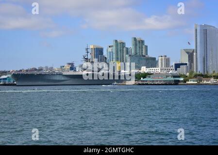 Die USS Midway, das historische Schlachtschiff des Flugzeugträgers, das heute ein Museum ist, befindet sich im Hafen von San Diego mit der Skyline der Innenstadt von San Diego im Hintergrund Stockfoto