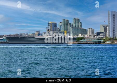 Die USS Midway, das historische Schlachtschiff des Flugzeugträgers, das heute ein Museum ist, befindet sich im Hafen von San Diego mit der Skyline der Innenstadt von San Diego im Hintergrund Stockfoto