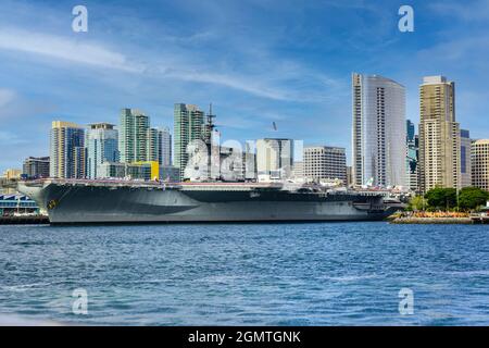 Die USS Midway, das historische Schlachtschiff des Flugzeugträgers, das heute ein Museum ist, befindet sich im Hafen von San Diego mit der Skyline der Innenstadt von San Diego im Hintergrund Stockfoto