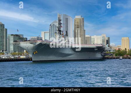 Die USS Midway, das historische Schlachtschiff des Flugzeugträgers, das heute ein Museum ist, befindet sich im Hafen von San Diego mit der Skyline der Innenstadt von San Diego im Hintergrund Stockfoto