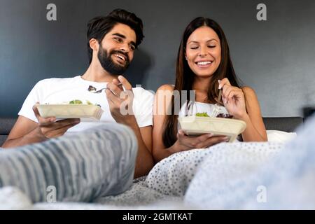 Gesundes Frühstück im Bett. Junge schöne Paar in der Liebe sitzt auf dem Bett und mit Frühstück. Stockfoto