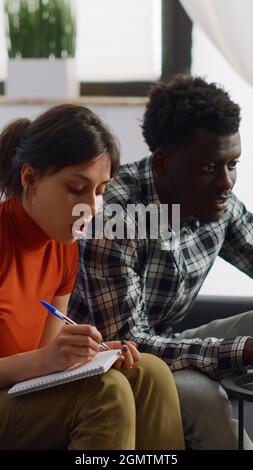 Interracial paar tun Steuern Zahlung mit Laptop im Wohnzimmer. Junge gemischte Rennpartner berechnen Geld und Budget für die Finanzplanung und zahlen Rechnungen auf der Couch zu Hause Stockfoto