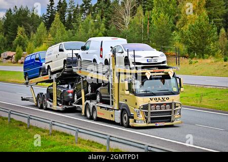 Goldfarbener Volvo FM-Autotransporter von Kawa Auto Oy transportiert Fahrzeuge im Autobahnverkehr an einem Herbsttag. Salo, Finnland. 10. September 2021. Stockfoto