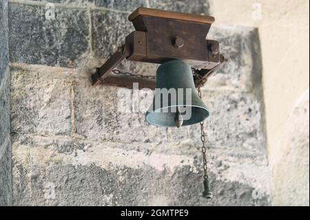 Alte Glocke hing an einer Steinmauer Stockfoto
