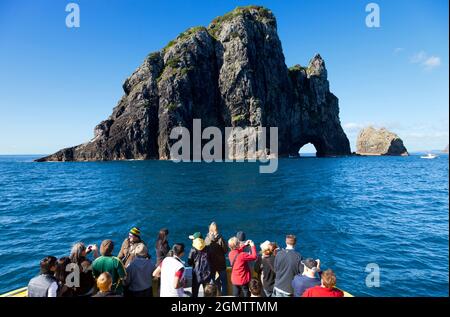 Bay of Islands, Neuseeland - 12. Mai 2012 Eine Gruppe von Touristen in einem Sightseeing-Boot hat die Möglichkeit, das Hole in the Rock, eine berühmte Erode, aus nächster Nähe zu sehen Stockfoto