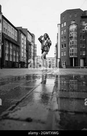 Mädchen in der Nähe Herbst Pfütze mit Reflexionen auf dem Stadtplatz Stockfoto