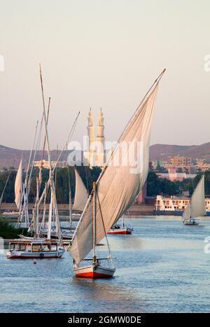 Assuan, Ägypten - 2. Dezember 2010; Eine magische Szene, wie die Dämmerung über dem Nil bei Assuan fällt - eine Felucca in vollem Verkauf mit Moscheen im Hintergrund. Th Stockfoto