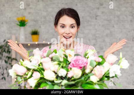 Junges Mädchen mit überrascht werden erhält Blumenstrauß. Frau erhält Geburtstagsgeschenk. Glückliches Mädchen hält Strauß von Rosen Stockfoto