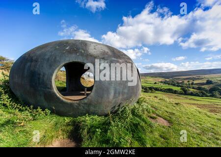 Design von Peter Meacock mit Katarina Novomestska und Architecture Central Workshop. Pendle's Panopticon, 'Atom', liegt auf dem Hügel über dem Dorf Wycoller im Wycoller Country Park. Sie besteht aus Ferrozement mit einer Oberflächenbeschichtung auf Metallbasis und ist sowohl ein beeindruckender moderner Aussichtspunkt als auch ein Zufluchtsort, von dem aus Sie die herrliche Landschaft von Pendle genießen können, als auch ein faszinierendes und schönes Objekt, das von weitem betrachtet werden kann. Von innen bieten die kreisförmigen Aussichtsräume einen spektakulären Blick auf die umliegende Landschaft. Wycoller ist eine historische Siedlung, die über 1000 v. Chr. hinausgeht. Stockfoto