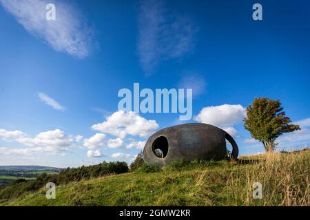 Design von Peter Meacock mit Katarina Novomestska und Architecture Central Workshop. Pendle's Panopticon, 'Atom', liegt auf dem Hügel über dem Dorf Wycoller im Wycoller Country Park. Sie besteht aus Ferrozement mit einer Oberflächenbeschichtung auf Metallbasis und ist sowohl ein beeindruckender moderner Aussichtspunkt als auch ein Zufluchtsort, von dem aus Sie die herrliche Landschaft von Pendle genießen können, als auch ein faszinierendes und schönes Objekt, das von weitem betrachtet werden kann. Von innen bieten die kreisförmigen Aussichtsräume einen spektakulären Blick auf die umliegende Landschaft. Wycoller ist eine historische Siedlung, die über 1000 v. Chr. hinausgeht. Stockfoto