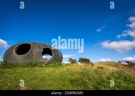 Design von Peter Meacock mit Katarina Novomestska und Architecture Central Workshop. Pendle's Panopticon, 'Atom', liegt auf dem Hügel über dem Dorf Wycoller im Wycoller Country Park. Sie besteht aus Ferrozement mit einer Oberflächenbeschichtung auf Metallbasis und ist sowohl ein beeindruckender moderner Aussichtspunkt als auch ein Zufluchtsort, von dem aus Sie die herrliche Landschaft von Pendle genießen können, als auch ein faszinierendes und schönes Objekt, das von weitem betrachtet werden kann. Von innen bieten die kreisförmigen Aussichtsräume einen spektakulären Blick auf die umliegende Landschaft. Wycoller ist eine historische Siedlung, die über 1000 v. Chr. hinausgeht. Stockfoto