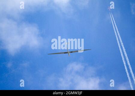 Radley Village, Oxfordshire, Großbritannien - April 2020; Kontraste - ein Segelflugzeug und Jet fliegen über meinem Heimatdorf Radley bei klarem Sommerhimmel. Das ist Progr Stockfoto