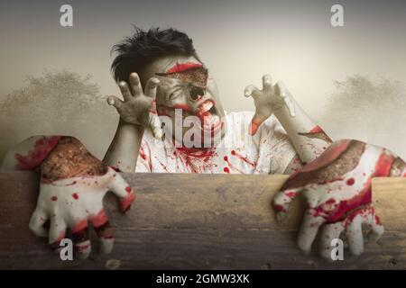 Furchteinflößende Zombies, die hinter der Holzwand mit dem dramatischen Szenenhintergrund stehen Stockfoto