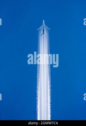 Radley Village, Oxfordshire, Großbritannien - April 2020; Kontraste - Ein Jjet, der über meinem Heimatdorf Radley bei klarem Sommerhimmel fliegt. Für den Fall, dass Sie sich wundern Stockfoto