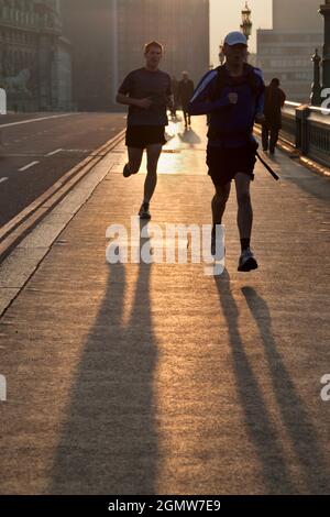 London, England - 2012; Verloren in einer Welt ihrer eigenen Jogger bei Sonnenaufgang auf der Westminster Bridge, London. Ich nehme an, es ist eine Möglichkeit, zur Arbeit zu kommen und fit zu bleiben Stockfoto