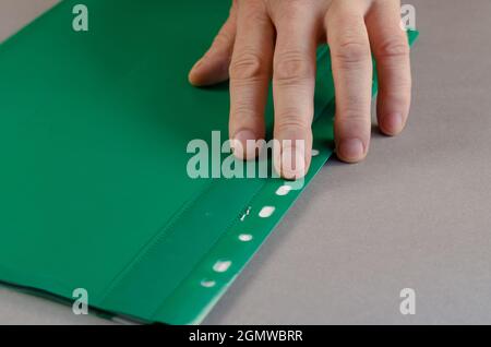 Reife männliche Hand liegt auf dem grünen Ordner. Person Druck Stockfoto