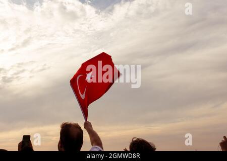 Izmir, Türkei - 9. September 2021: Menschen, die am Tag der Freiheit von Izmir eine türkische Flagge im Rahmen schwenken Stockfoto