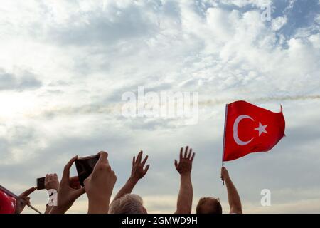 Izmir, Türkei - 9. September 2021: Menschen, die am Tag der Freiheit von Izmir eine türkische Flagge im Rahmen schwenken Stockfoto