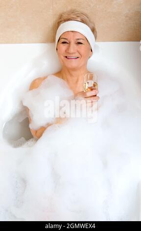 Vertikale Aufnahme einer älteren polnischen Frau, die auf einer mit Blasen gefüllten Badewanne liegt Stockfoto