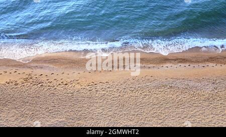 Blick auf die Meereswellen am Strand. Gelber Sand und blaues Wasser Stockfoto