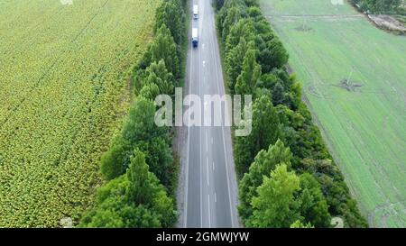 Die Bewegung von LKWs auf der Autobahn. Luftaufnahme von Fahrzeugen, die sich auf der Straße bewegen Stockfoto