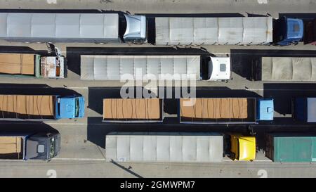 Draufsicht auf LKWs, die in der Schlange am Terminal stehen. Ladetransport mit Traktoren. Logistik-Transport auf dem Parkplatz. Stockfoto