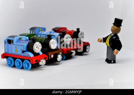 Der Fat Controller spricht mit Spielzeug-Druckguss-Motoren vor weißem Hintergrund Stockfoto