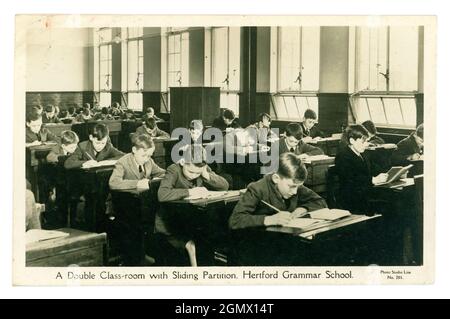 Originalpostkarte aus den 30er Jahren des 20. Jahrhunderts mit Doppelklassenzimmer, mit Schiebetrennung, Hertford Grammar School, jungen Jungen an Schreibtischen, von Studio Lisa U.K. Stockfoto