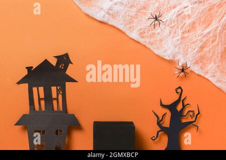 Halloween-Podien oder Sockel für Produktdisplay, schwarzes Haus und Baum mit Spinnennetz auf orangefarbenem Hintergrund. Halloween Weihnachtsschmuck. Stockfoto