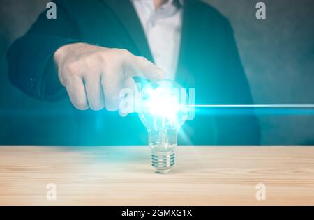 Idee Konzept. Geschäftsmann hält eine glühende Glühbirne in der Hand auf blauem Hintergrund. Banner. Business-Mann Hand hält Glühbirne, Idee spart Energie. Stockfoto