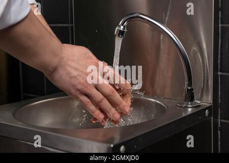 Nahaufnahme von Männern, die sich mit Wasser die Hände waschen. Stockfoto