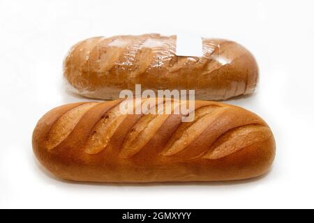 Weißes frisches Brot mit einer knusprigen Kruste steht in einem Regal in einer Bäckerei zum Verkauf Stockfoto