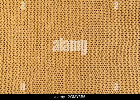 Nahaufnahme von goldfarbenem Strickstoff, textiler Hintergrund Stockfoto
