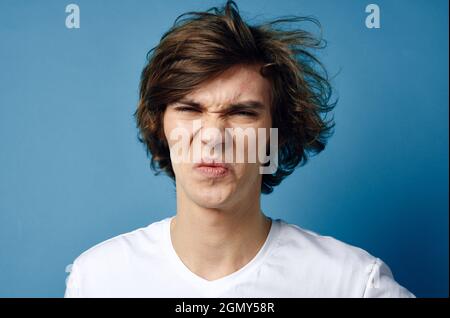 Kerl in weißem T-Shirt quetscht Pickel auf seinem Gesicht Teenager Stockfoto