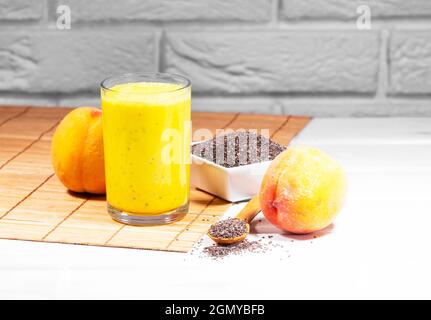 Stillleben mit Frucht-Smoothie, Pfirsich- und Chiasamen auf weißem Backstein-Hintergrund, vertikaler Auflösung, gesunder Sommerdiät, Copy Space Stockfoto