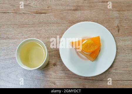 Orangenkuchen mit Sahneteig und heißer Teetasse auf dem Tisch Stockfoto