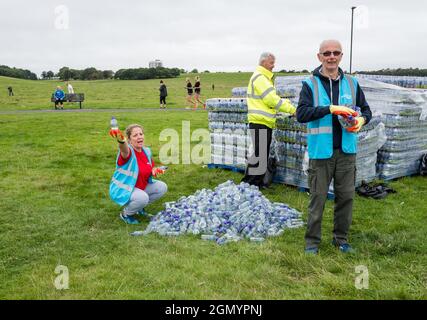 Freiwillige verteilen kostenlose Wasserflaschen an die Teilnehmer des Great North Run 2021. Stockfoto