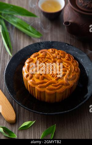 Mondkuchen mit chinesischem Tee. Das chinesische Schriftzeichen auf dem Mondkuchen stellt auf Englisch die „Pandan Lotus Paste“ dar Stockfoto