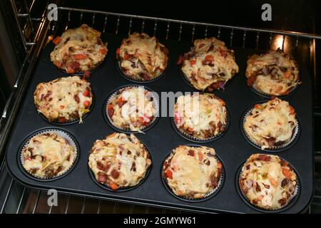 Backblech mit hausgemachten Pizza-Muffins auf einem Gitter im Ofen, ausgewählter Fokus, enge Schärfentiefe Stockfoto