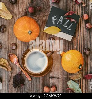 Tasse Kaffee, Kürbisse, bunte, verblasste Blätter, Kastanien, wilde Äpfel, Schild Inschrift Fall. Flach liegend, Draufsicht. Konzept des Laubfalles, Herbst. Stockfoto