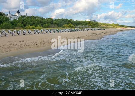 Sandstrand von Zinnowitz auf der Insel Usedom an der Ostsee mit Wellen, Strandliegen, Dünenvegetation und Hotels, unter wolkenbewittem Himmel, berühmten Touris Stockfoto